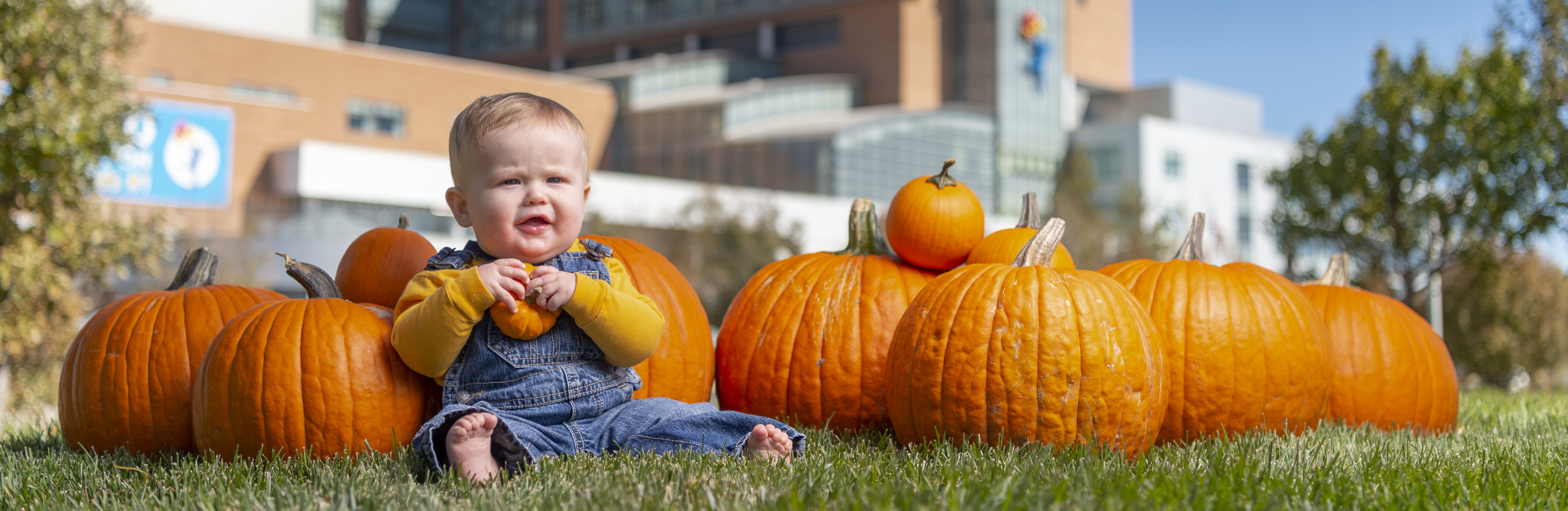 Infant surrounded by pumpkins outside of Children's Hospital Colorado Anschutz Medical Center